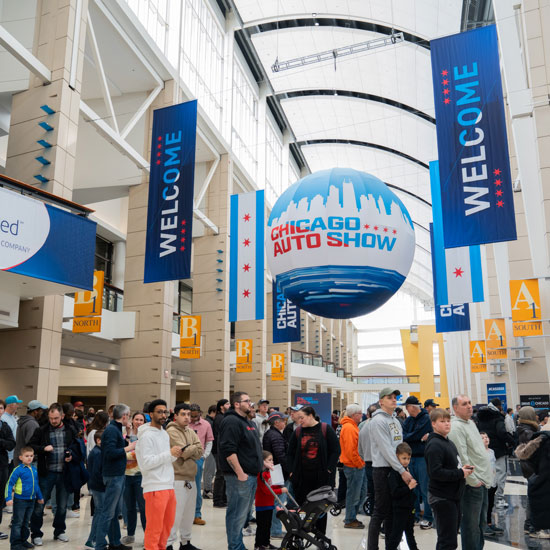 Highlights From the 2026 Chicago Auto Show; Crowd at the entrance of the Chicago Auto Show with large "Welcome" banners and a globe featuring the show's logo hanging above.