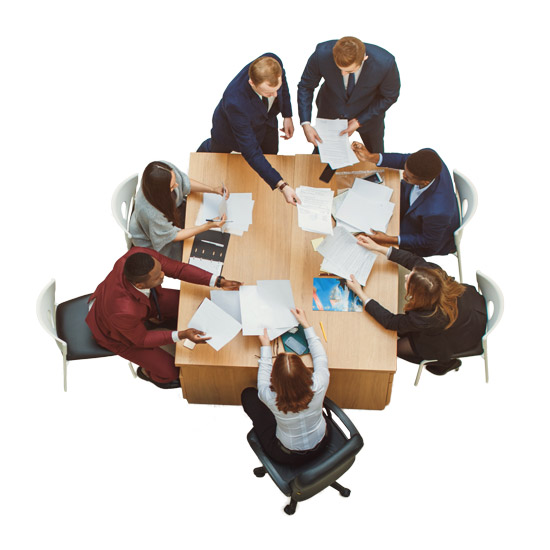 Strengthening Pension and Welfare Funds Through Leadership; Aerial view of a diverse group of professionals in suits sitting around a rectangular table, actively exchanging documents in a collaborative meeting.